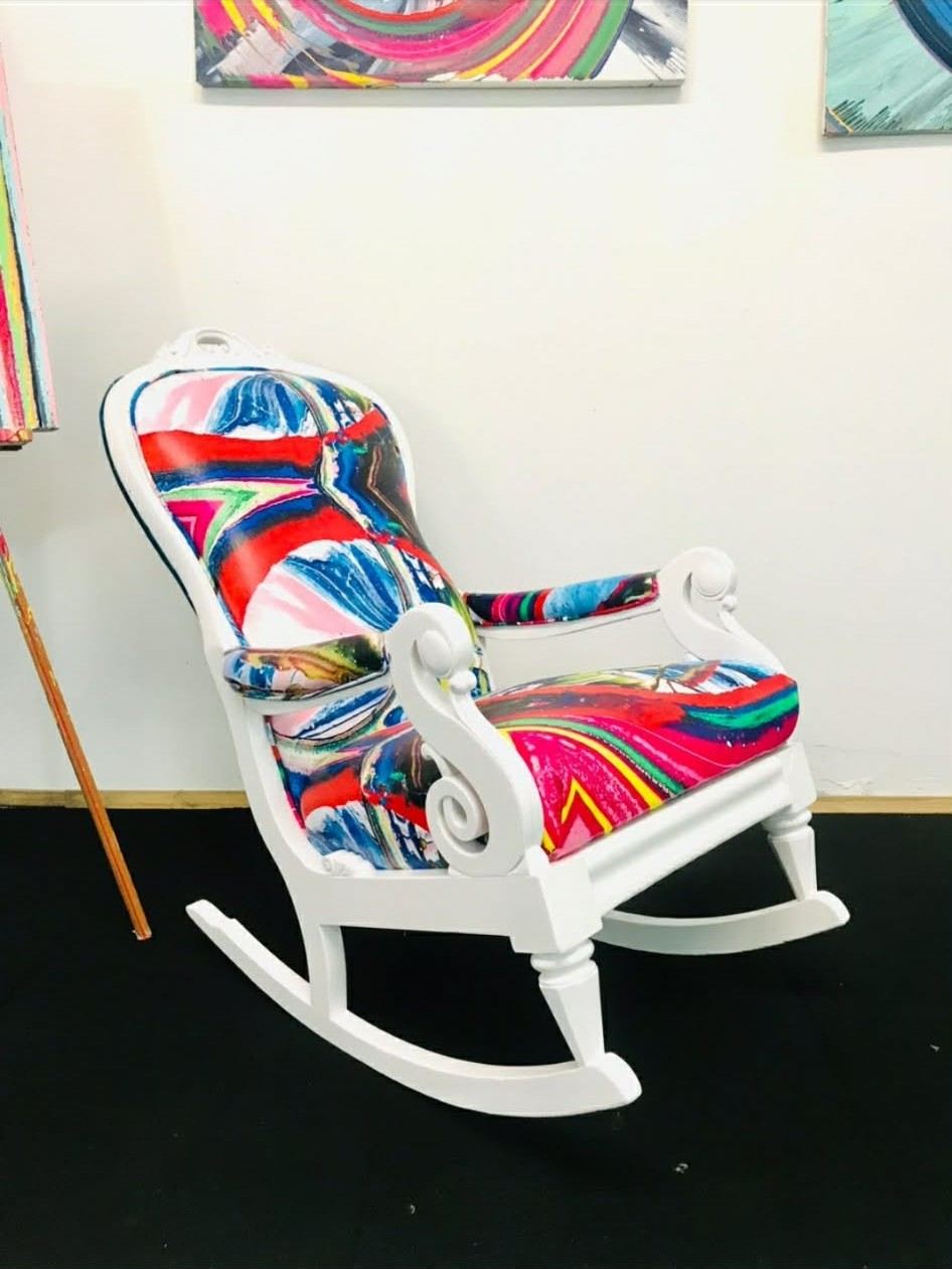 White rocking chair upholstered in red and blue abstract painting