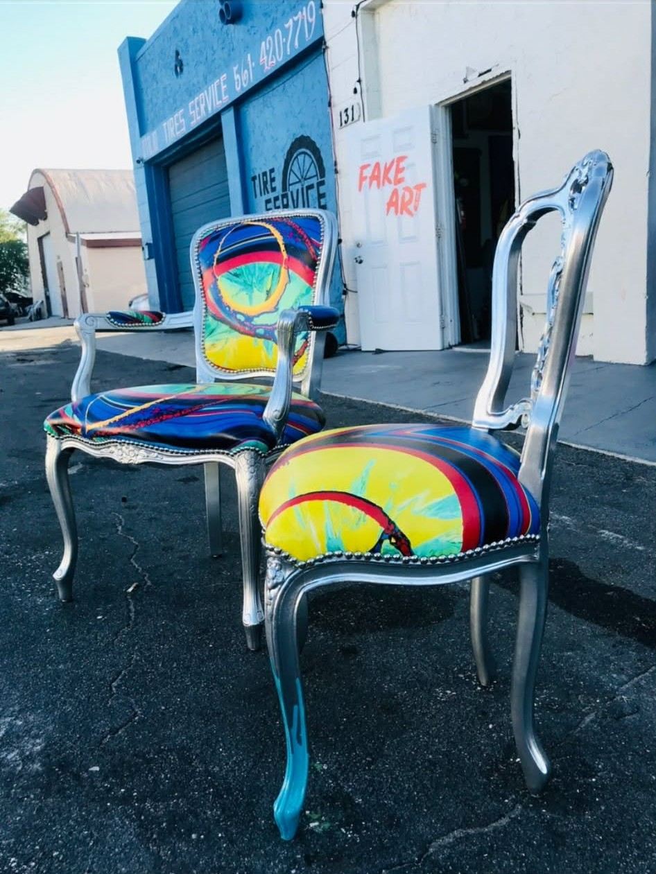 Two silver-frame chairs outside the studio door marked FAKE ART