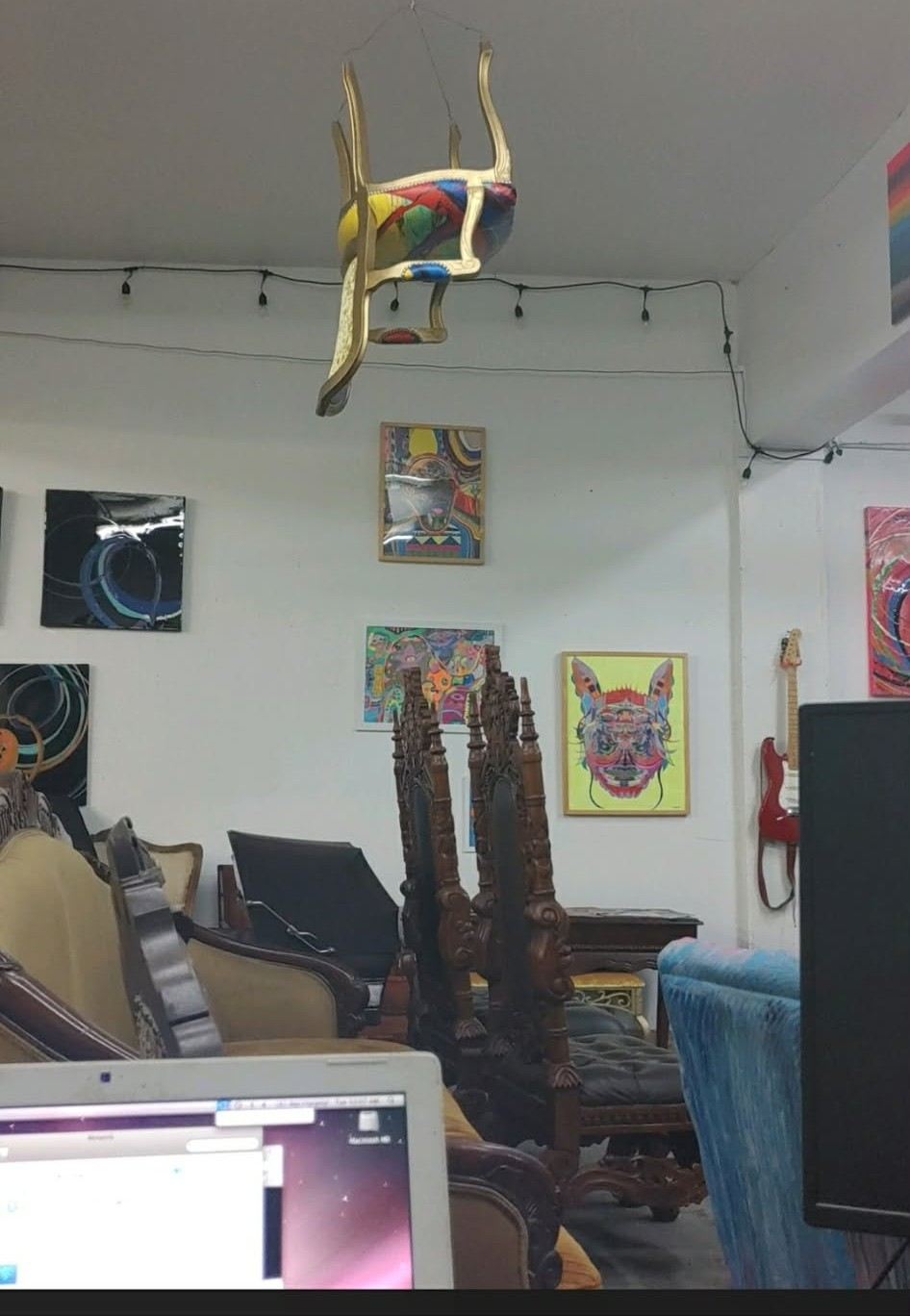 A gold painted chair hanging upside down from the studio ceiling